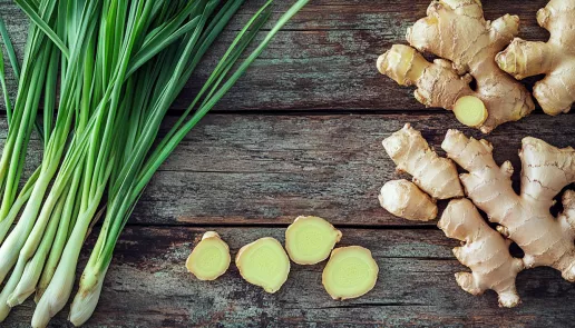 Fresh ginger roots and lemongrass stalks arranged on a wooden surface
