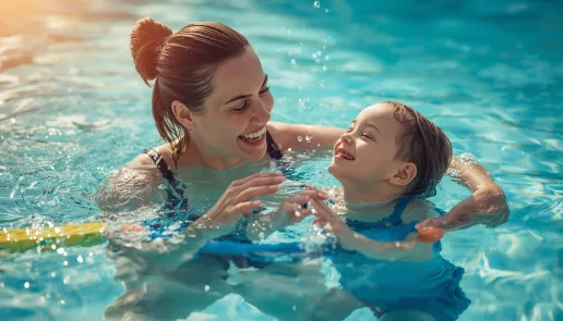 Parent teaching beginner swimming skills for kids in a shallow pool
